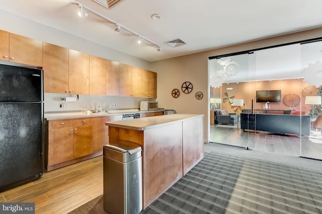 kitchen with a center island, dishwasher, sink, black fridge, and light hardwood / wood-style flooring