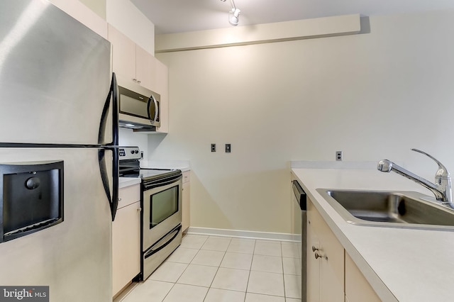 kitchen with rail lighting, light tile patterned floors, sink, and appliances with stainless steel finishes