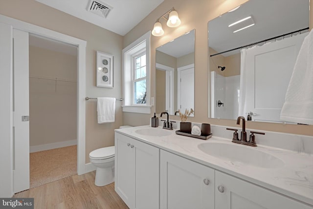 bathroom featuring a shower, vanity, wood-type flooring, and toilet