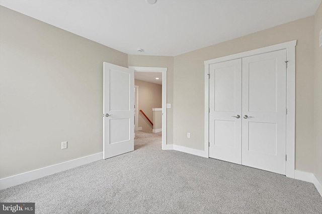 unfurnished bedroom featuring light carpet and a closet