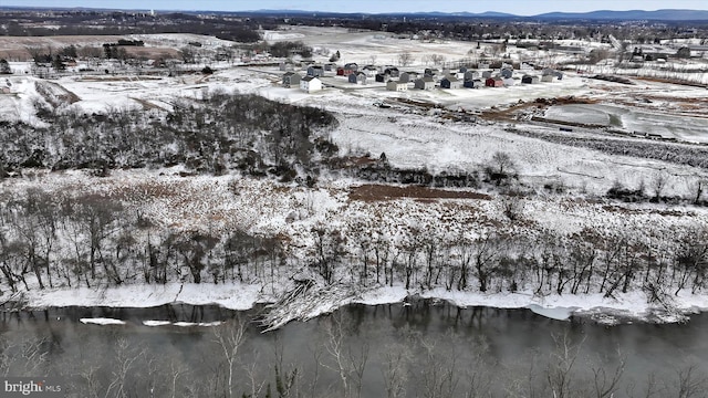 snowy aerial view featuring a water and mountain view