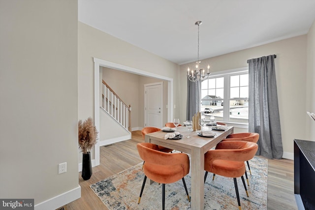 dining space with light hardwood / wood-style floors and a notable chandelier