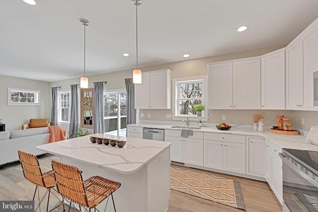 kitchen featuring a breakfast bar area, sink, white cabinets, and decorative light fixtures