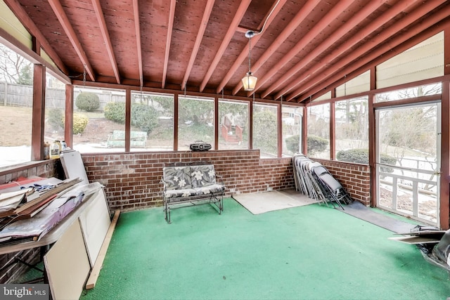 unfurnished sunroom featuring a healthy amount of sunlight and vaulted ceiling with beams