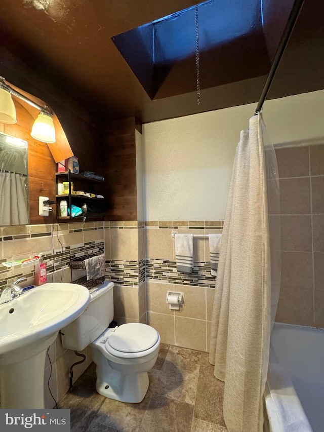 full bathroom featuring sink, toilet, shower / bath combo with shower curtain, and tile walls