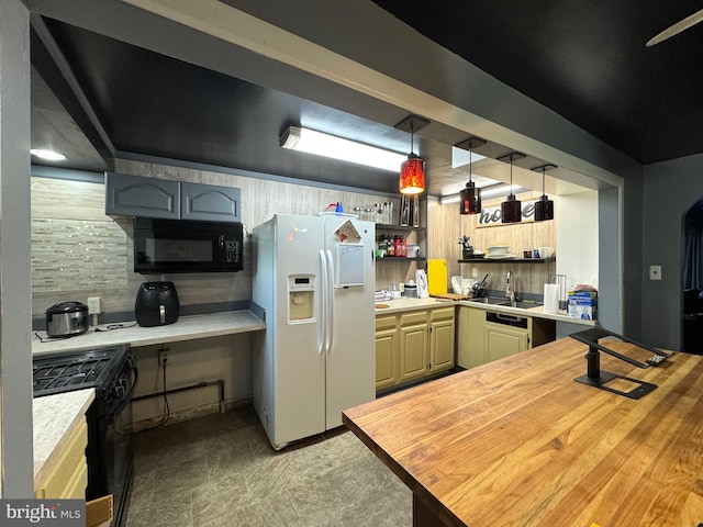 kitchen featuring sink, black appliances, decorative light fixtures, and wooden counters