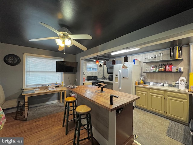 kitchen with black stove, white fridge with ice dispenser, wooden counters, a breakfast bar area, and light wood-type flooring