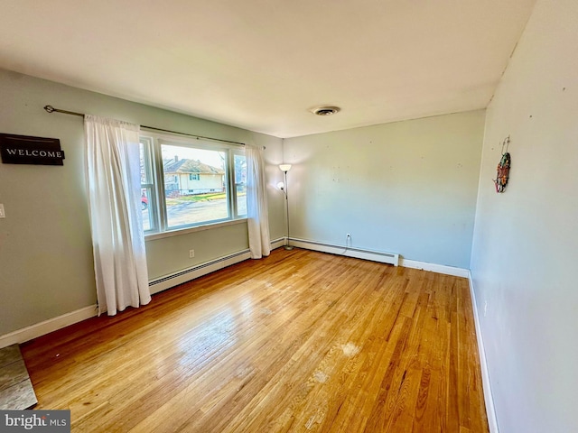 empty room with light wood-type flooring and baseboard heating