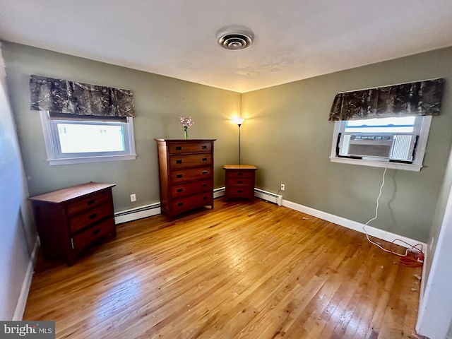 unfurnished bedroom featuring light hardwood / wood-style floors and a baseboard heating unit