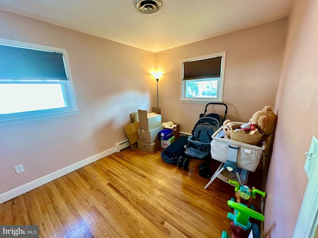 interior space with light hardwood / wood-style flooring, a wealth of natural light, and a baseboard heating unit