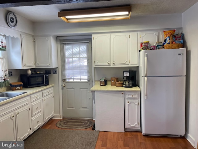 kitchen featuring dark hardwood / wood-style flooring, white refrigerator, and white cabinetry