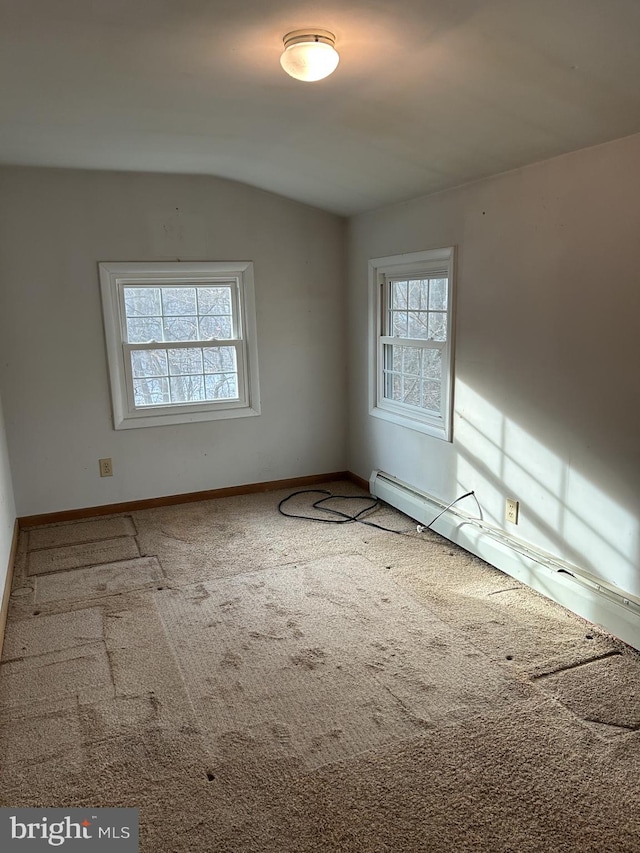 unfurnished room with a baseboard heating unit, vaulted ceiling, and carpet