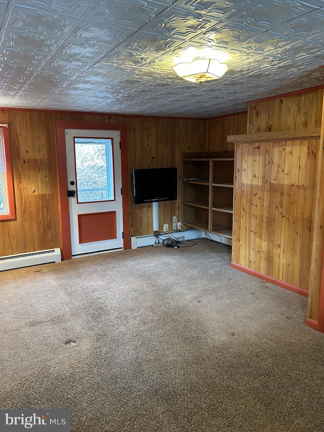 unfurnished living room with wooden walls, carpet, and baseboard heating