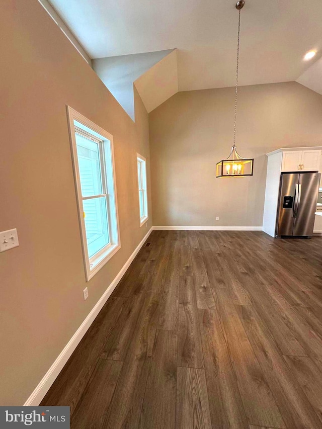 unfurnished dining area featuring lofted ceiling, dark hardwood / wood-style flooring, and an inviting chandelier