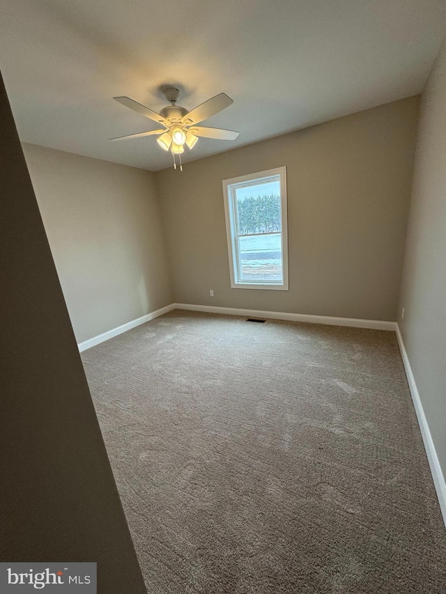 unfurnished room with ceiling fan and carpet