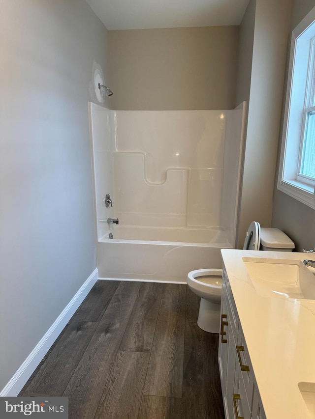 full bathroom featuring washtub / shower combination, hardwood / wood-style floors, toilet, and vanity