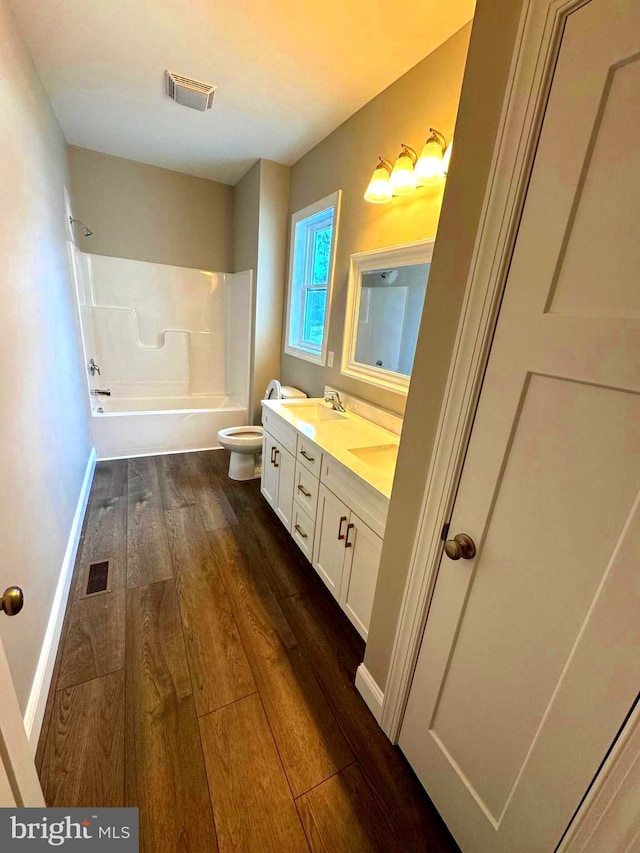 full bathroom featuring hardwood / wood-style flooring, washtub / shower combination, toilet, and vanity