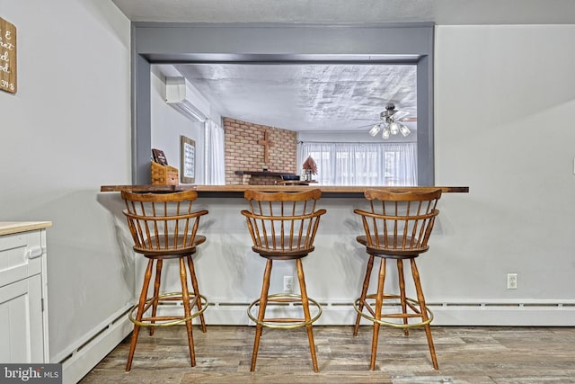 bar featuring hardwood / wood-style floors, ceiling fan, and a baseboard radiator