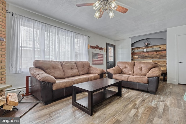 living room featuring light wood-type flooring, a textured ceiling, plenty of natural light, and ceiling fan