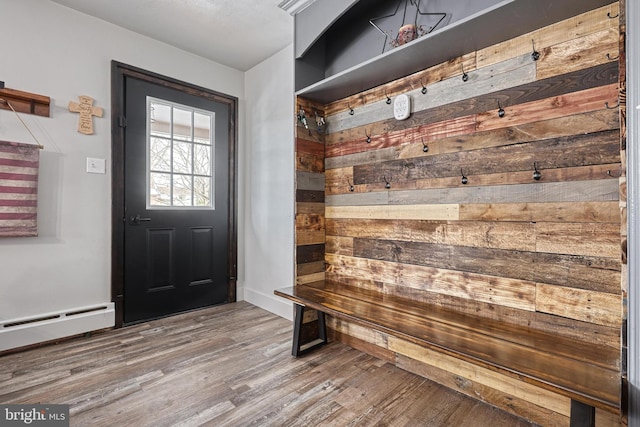 mudroom with baseboard heating, wood walls, and hardwood / wood-style floors