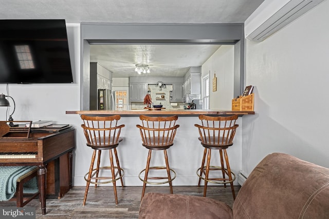 bar featuring stainless steel fridge and dark hardwood / wood-style floors