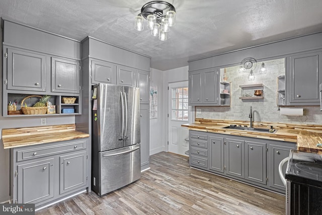 kitchen featuring wooden counters, stainless steel fridge, sink, range, and gray cabinets