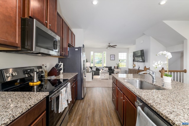 kitchen with light stone countertops, appliances with stainless steel finishes, ceiling fan, sink, and dark hardwood / wood-style floors