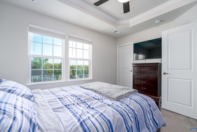 carpeted bedroom with a tray ceiling, ceiling fan, and ornamental molding