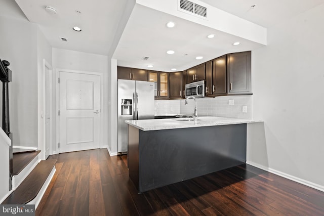 kitchen featuring kitchen peninsula, dark brown cabinetry, stainless steel appliances, sink, and dark hardwood / wood-style floors