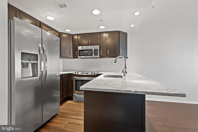 kitchen featuring appliances with stainless steel finishes, dark hardwood / wood-style floors, dark brown cabinets, and sink