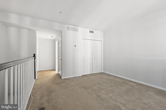 unfurnished bedroom featuring a closet and light colored carpet