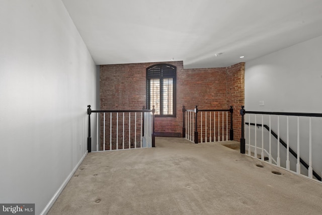 empty room with carpet flooring and brick wall