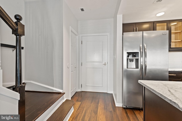 kitchen featuring light stone counters, stainless steel refrigerator with ice dispenser, tasteful backsplash, and dark wood-type flooring