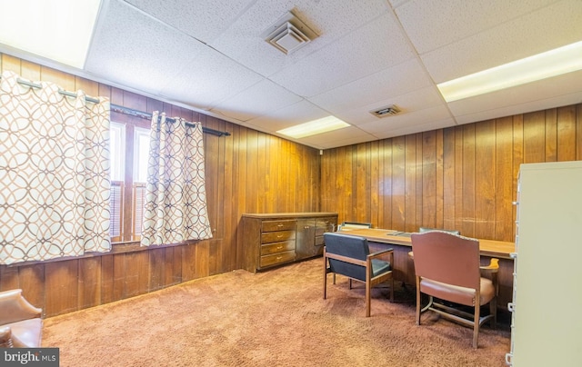 carpeted office featuring a drop ceiling and wooden walls