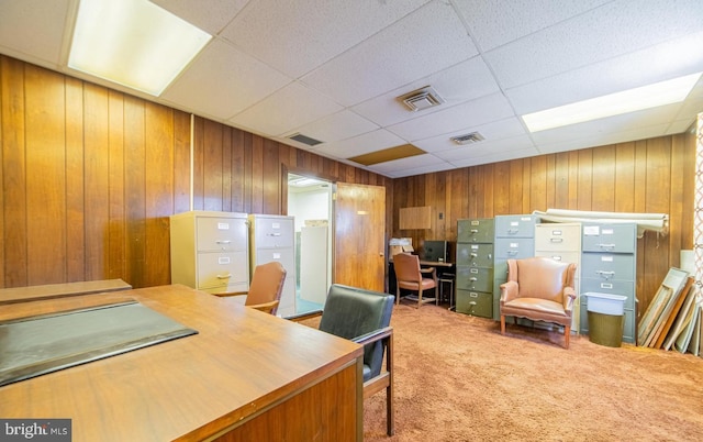 office area featuring a drop ceiling, wood walls, and carpet floors