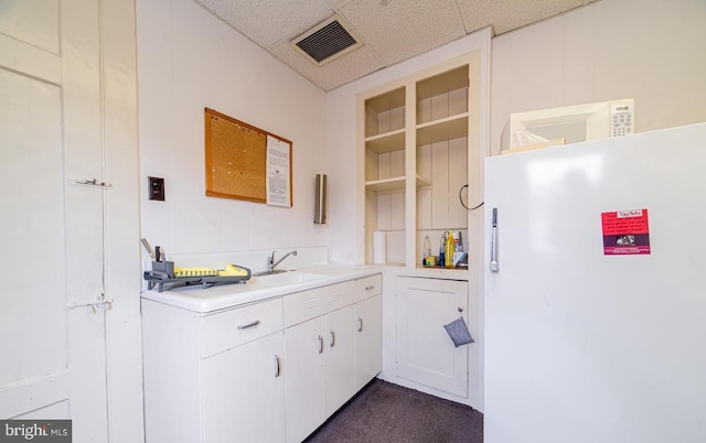 kitchen with white cabinets, a drop ceiling, and sink