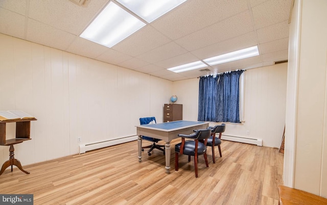 dining area with a drop ceiling, light wood-type flooring, and a baseboard heating unit