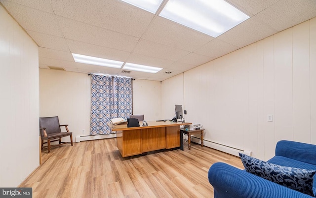 office space with a paneled ceiling, a baseboard radiator, and light hardwood / wood-style flooring