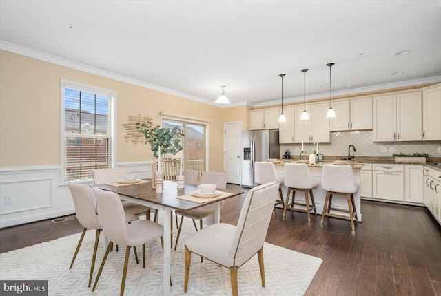 dining room featuring crown molding, sink, and dark wood-type flooring