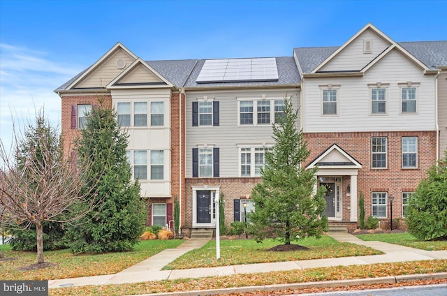 multi unit property featuring a front yard and solar panels