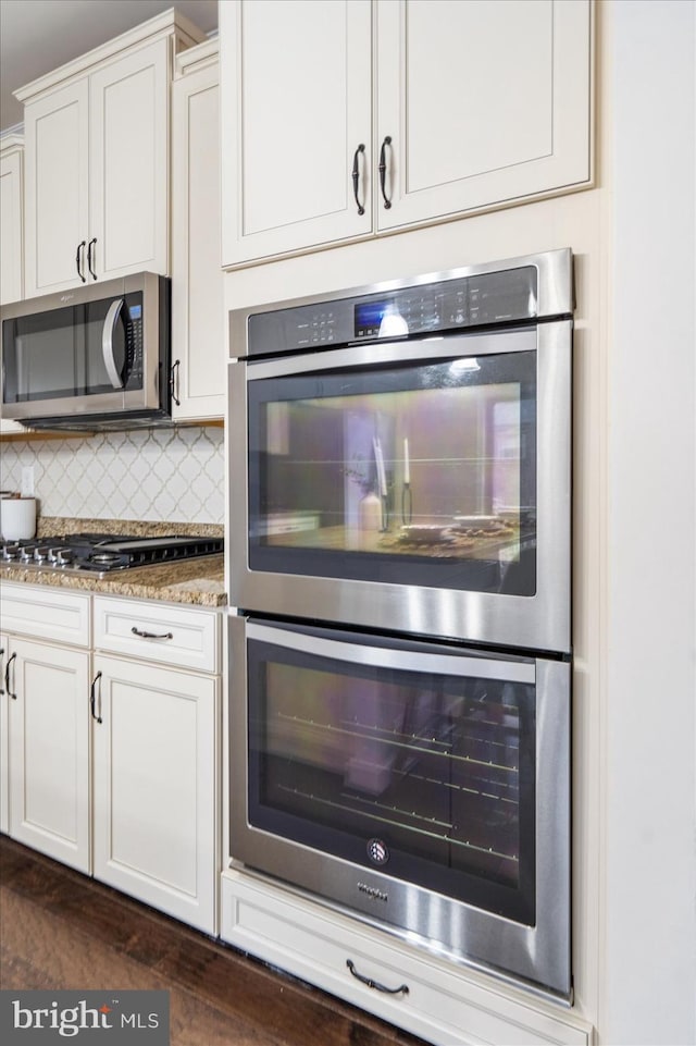 kitchen with dark stone counters, tasteful backsplash, white cabinets, and stainless steel appliances