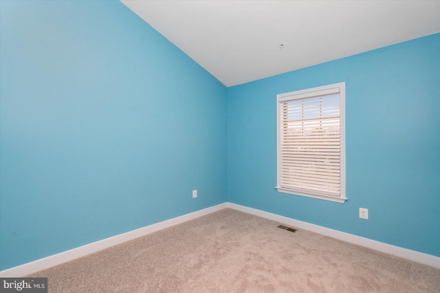 carpeted empty room with lofted ceiling