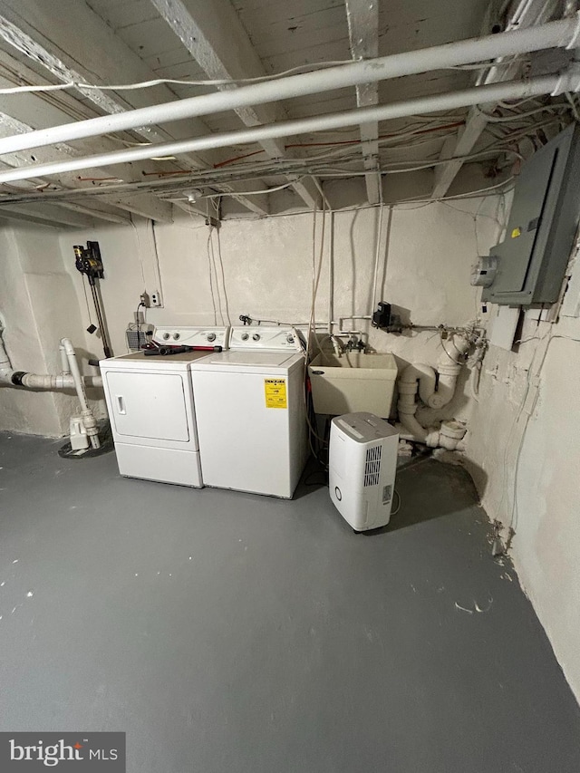 basement with electric panel, washer and clothes dryer, and sink