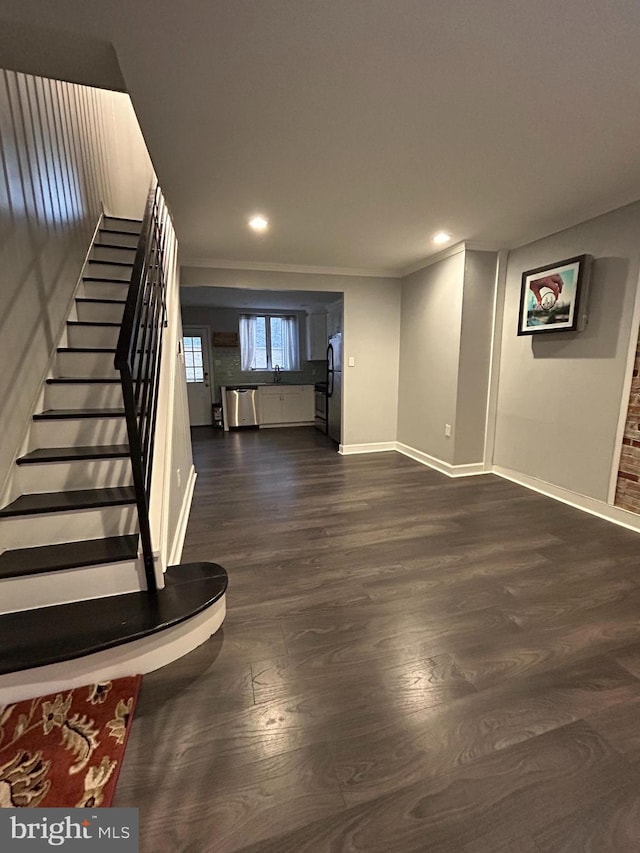 interior space with stainless steel refrigerator, crown molding, dark hardwood / wood-style flooring, and sink