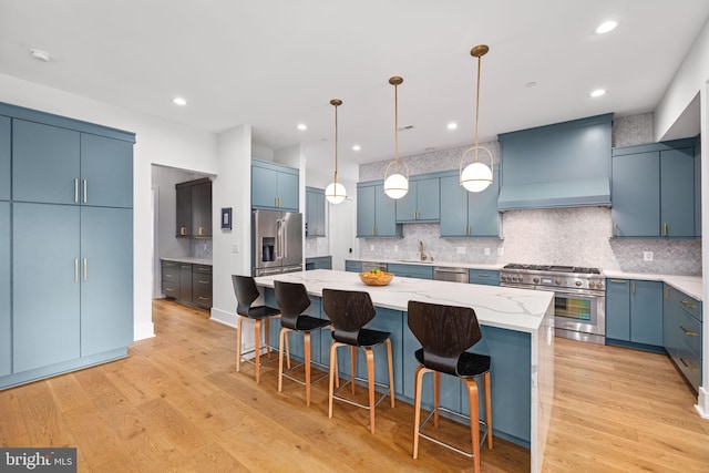 kitchen featuring a kitchen island, blue cabinets, premium range hood, and appliances with stainless steel finishes