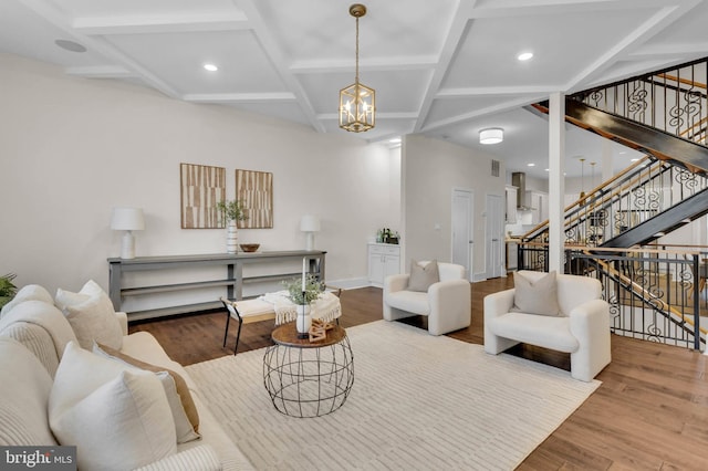 living room with an inviting chandelier, wood-type flooring, and coffered ceiling