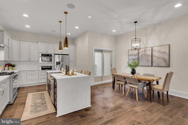 kitchen featuring stainless steel appliances, white cabinetry, pendant lighting, and a center island with sink