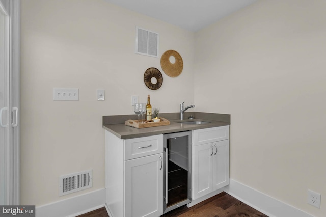 bar featuring wine cooler, sink, dark wood-type flooring, and white cabinets