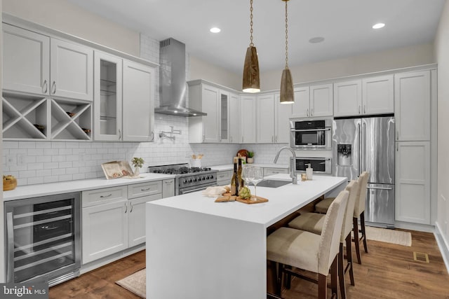 kitchen with wall chimney range hood, stainless steel appliances, beverage cooler, and white cabinets