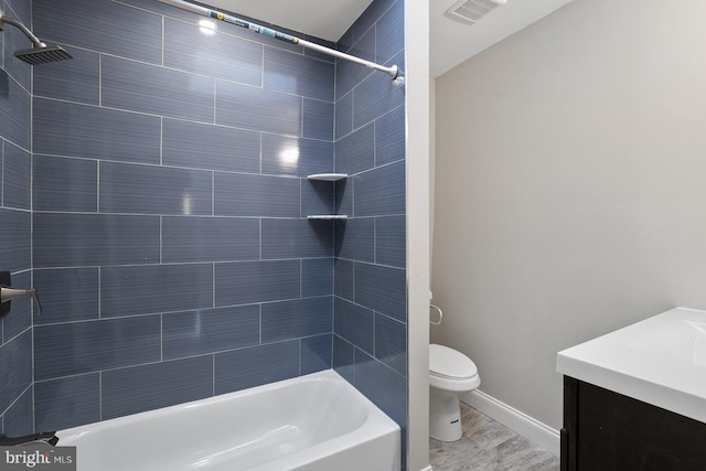 full bathroom with hardwood / wood-style floors, vanity, toilet, and tiled shower / bath